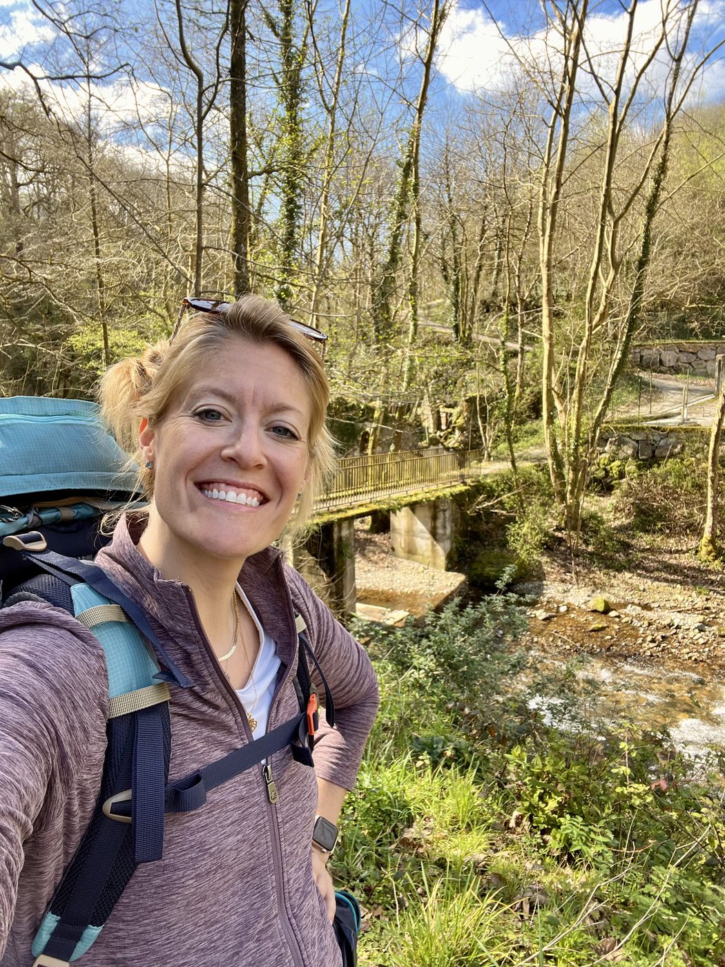 Melanie smiling on a forest hike with her backpack on